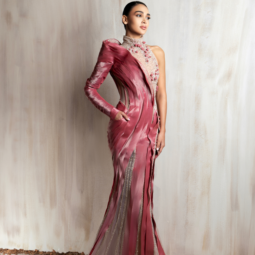 Rose pink sculpted satin gown with sheer beaded panels and a one-shoulder sleeve, crafted for modern elegance. Shop now at our exclusive clothing website.