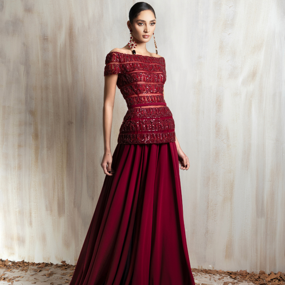 Deep red off-shoulder gown with a beaded bodice and flowing crepe-georgette skirt. Shop now at our exclusive clothing website.