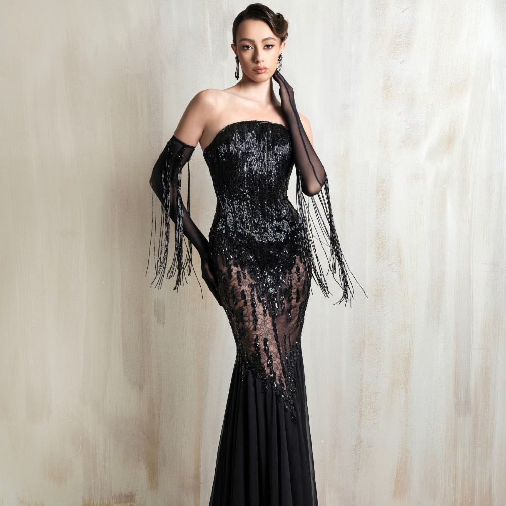 Black strapless lace gown with sheer gloves and fringe details, crafted for glamorous elegance. Shop now at our exclusive clothing website.