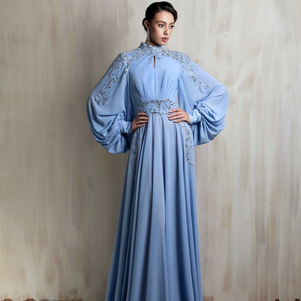 Powder blue gown with embroidered cape sleeves, crafted for elegant occasions and timeless charm. Shop now at our exclusive clothing website.