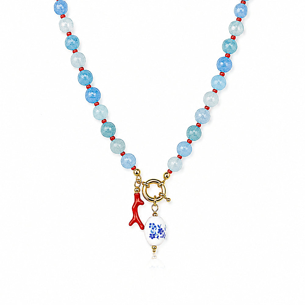 Discover the Azure Reef Agate Beaded Necklace at The Luxe Maison, featuring blue agate beads, vibrant red accents, a coral branch charm, and a blue-and-white porcelain bead for a playful, ocean-inspired look.