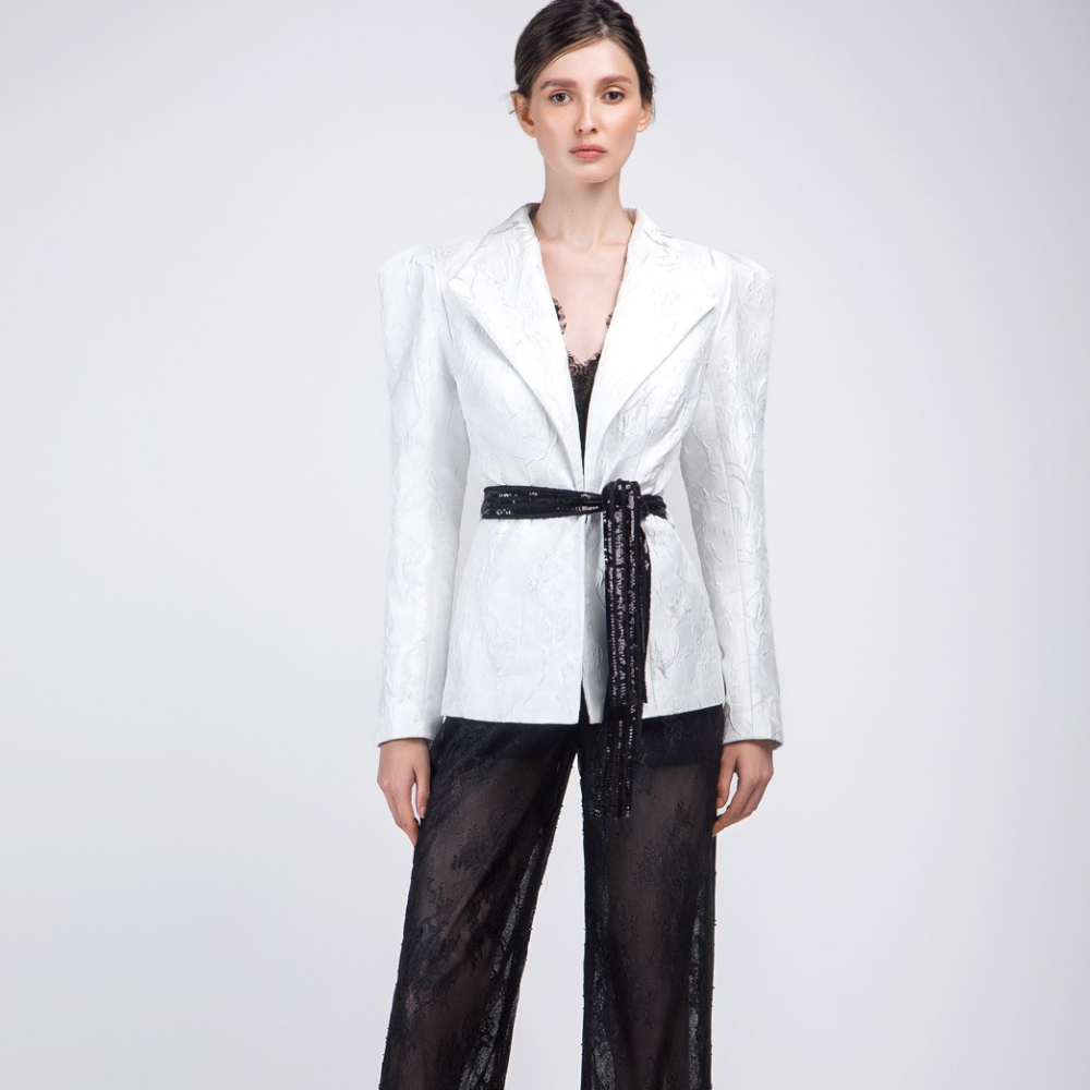 The black lace fabric sleeveless jumpsuit comes with a brocade white color jacket and embroidered black sequins belt.