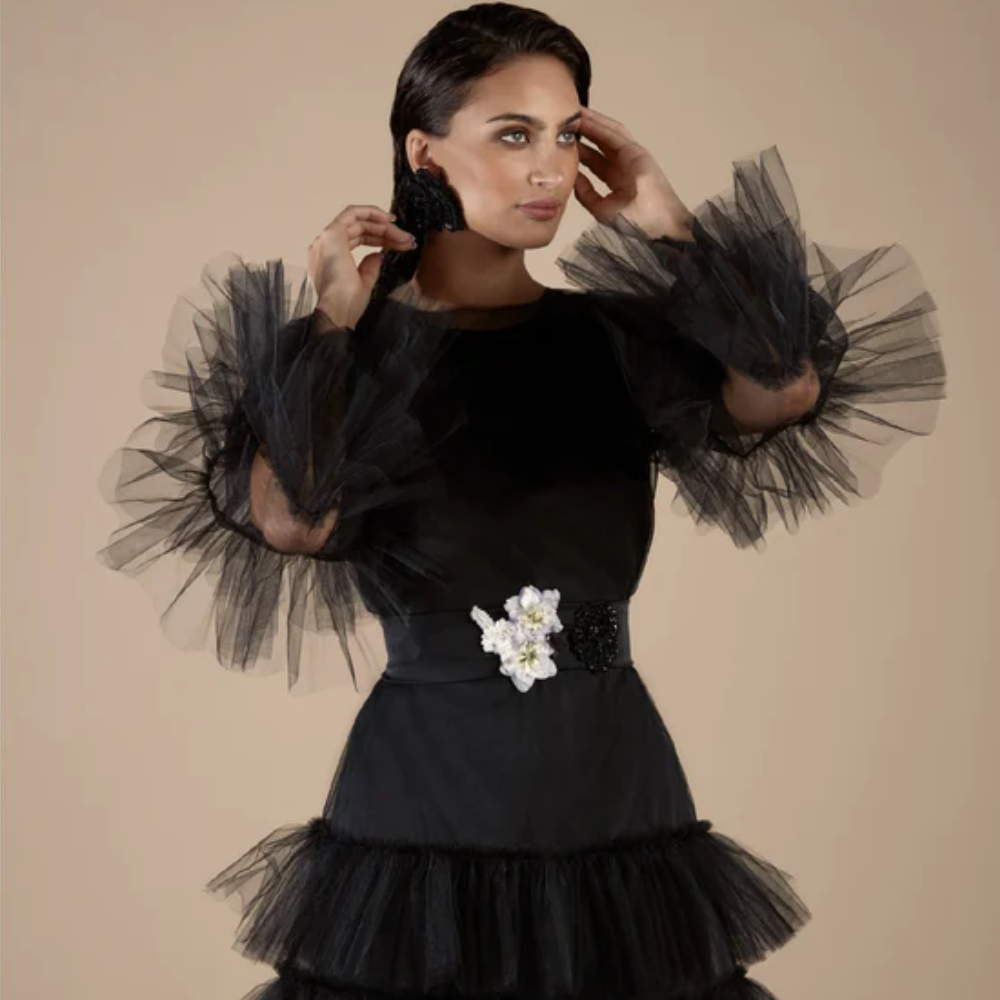 A black tulle ruffled mini dress exudes timeless elegance with its delicate layers and playful flair. 
