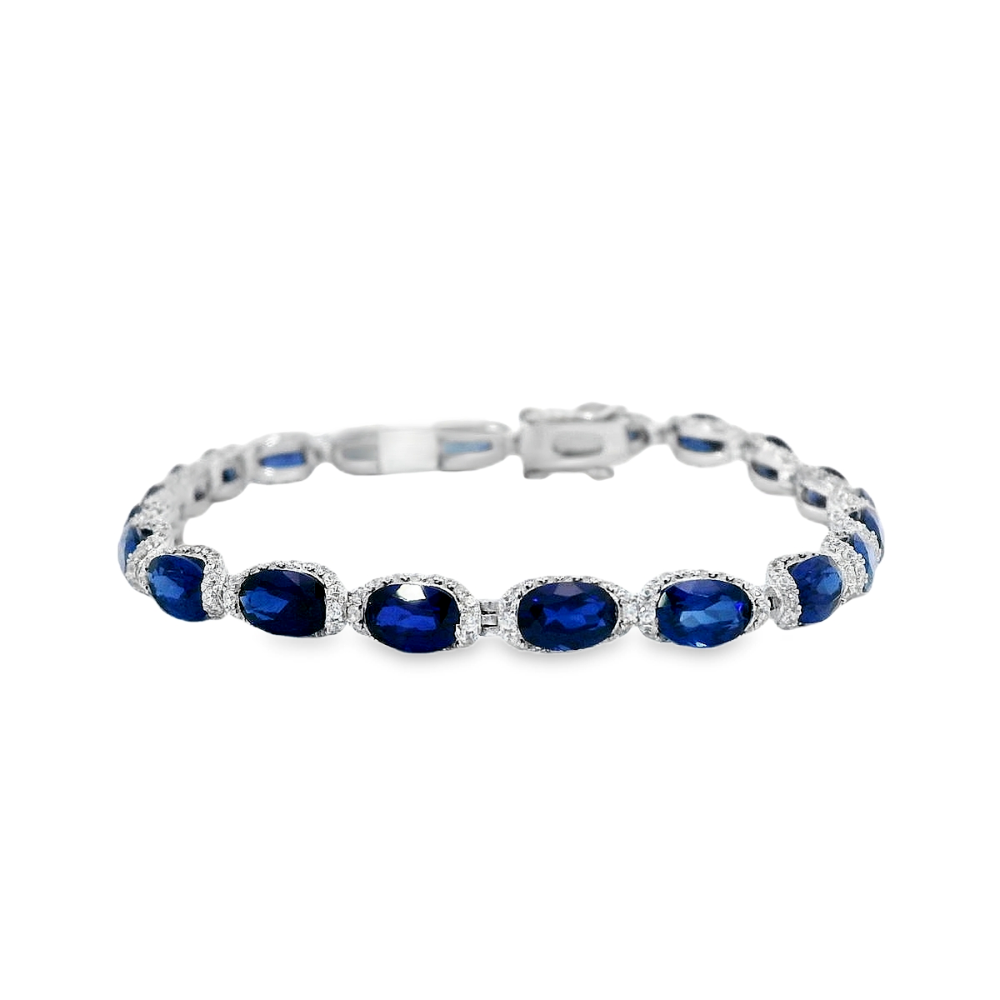 Sterling silver rhodium plated tennis bracelet featuring oval lab-created blue sapphires surrounded by sparkling cubic zirconia for a timeless statement look. Shop premium jewelry online.