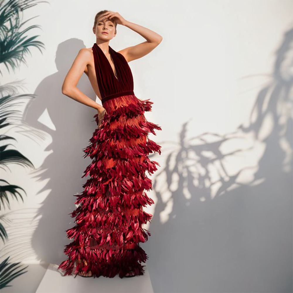 A Burgundy velvet dress with a deep V neckline and a skirt in ruffled feathers