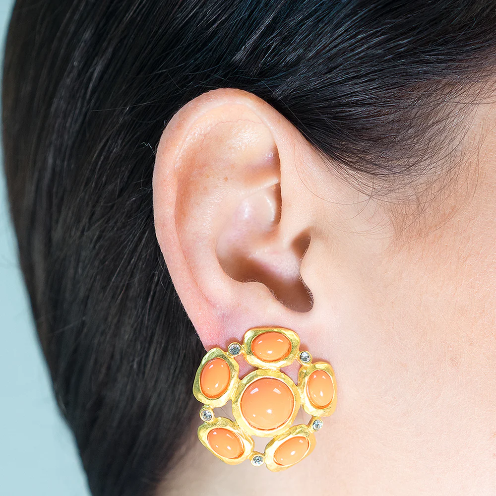 Satin gold clip earring with small crystal accents and bold coral cabochons.