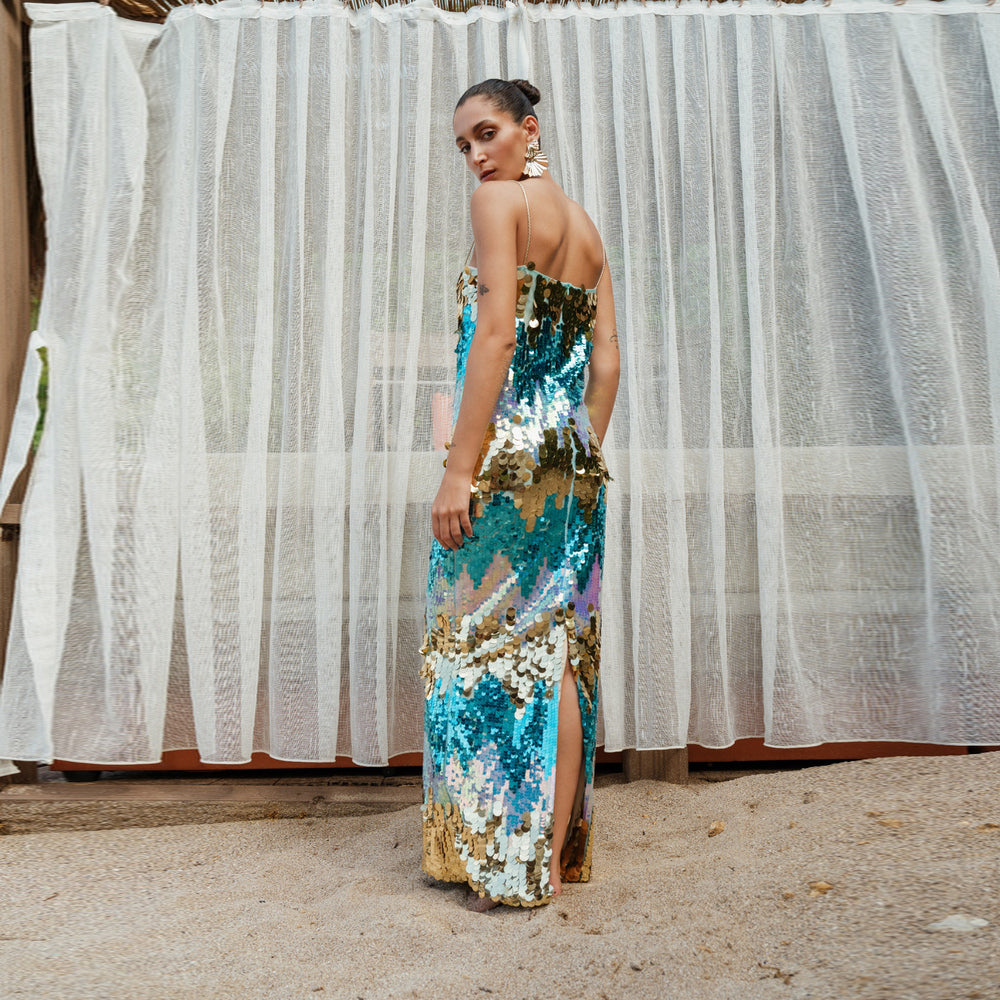 Shop online from our exclusive website and discover the Dila Dress by Nana Gotti, featuring turquoise and gold sequins with a collarbone-baring silhouette for elegant statement style.