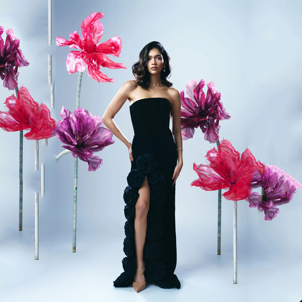 Black velvet corset gown with slit and rose detail, perfect for evening events. Shop online from our curated edit of premium fashion.
