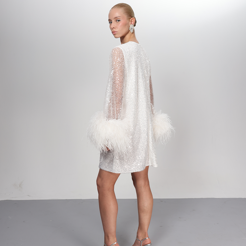 This exquisite dress, meticulously hand-sewn and adorned with splendid feathers cascading around the sleeves.