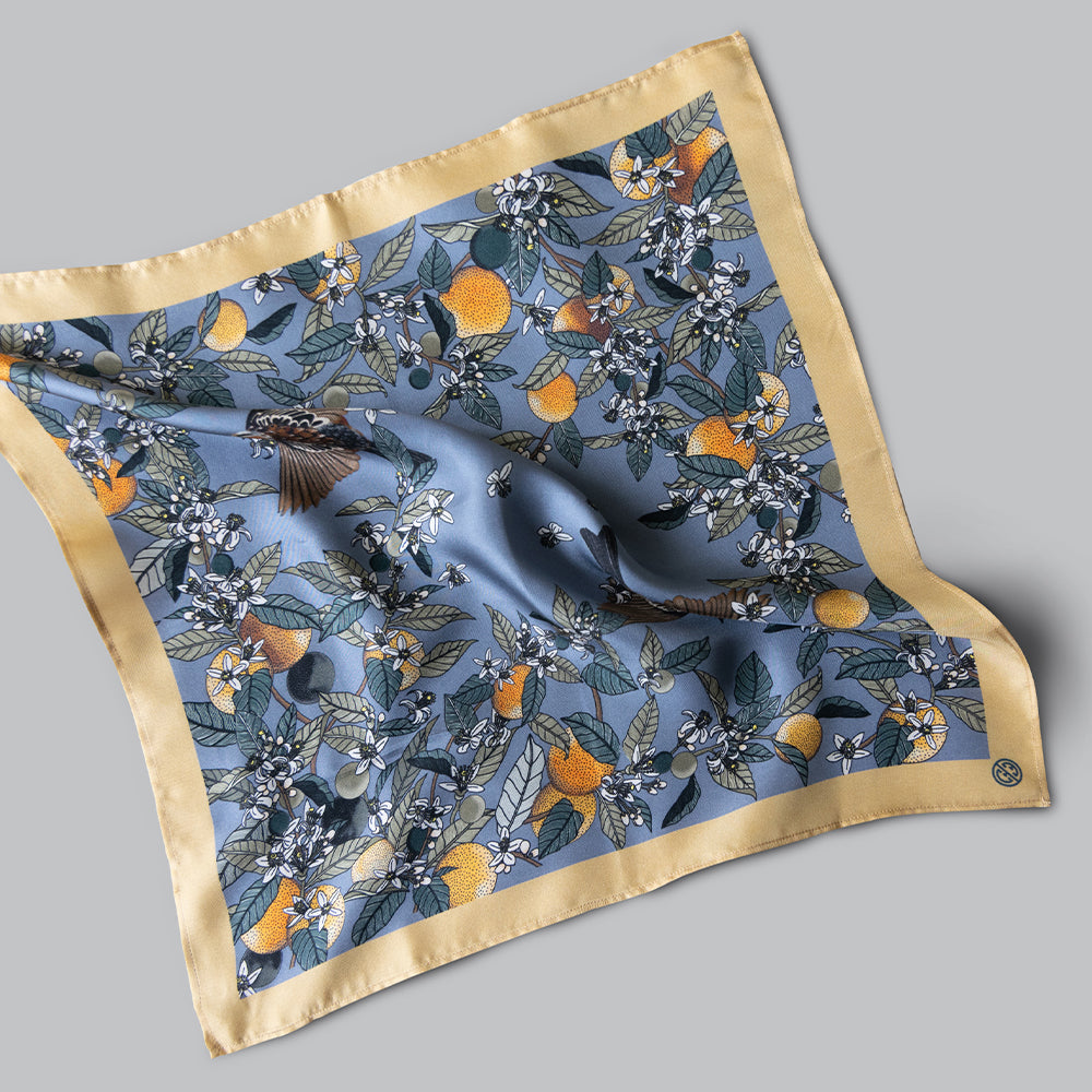A stonewashed blue mini square with orange blossoms and fruit delicately hand-illustrated.