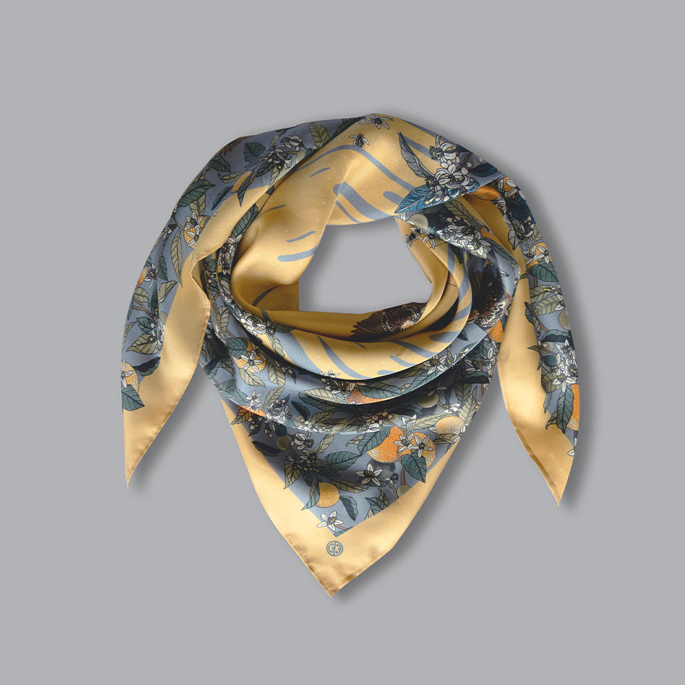 A stonewashed blue scarf with orange blossoms and fruit delicately hand-illustrated, and sparrows hidden under the stems.