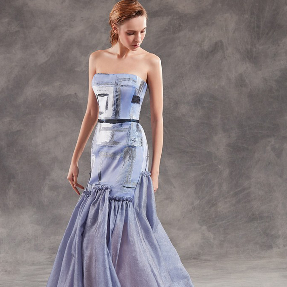 This strapless mermaid gown in organza with metallic tulle panels on the skirt.