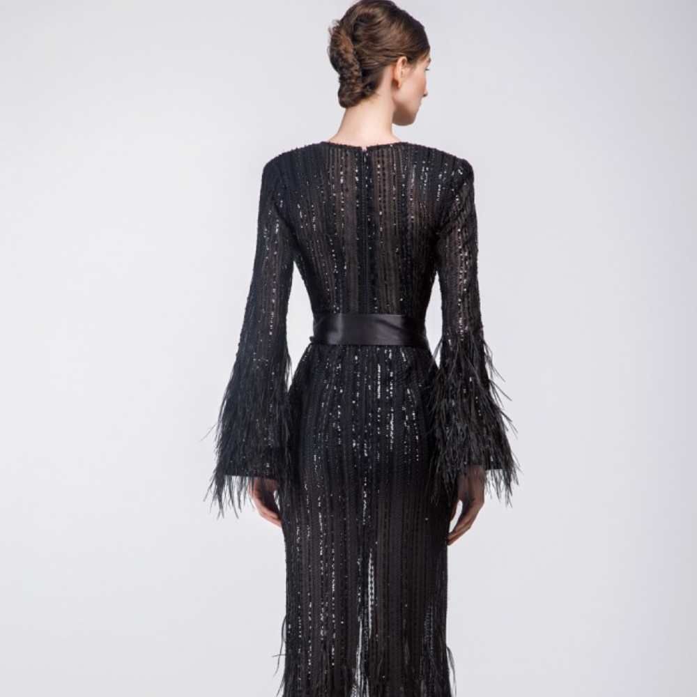 Fully beaded long wrapped black dress with feathers on the bottom of the sleeves and the skirt.