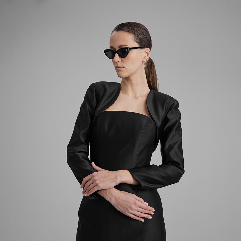 Explore our curation of designer gowns with Gigi black strapless dress with a bolero jacket that showcases a timeless silhouette. Shop now!