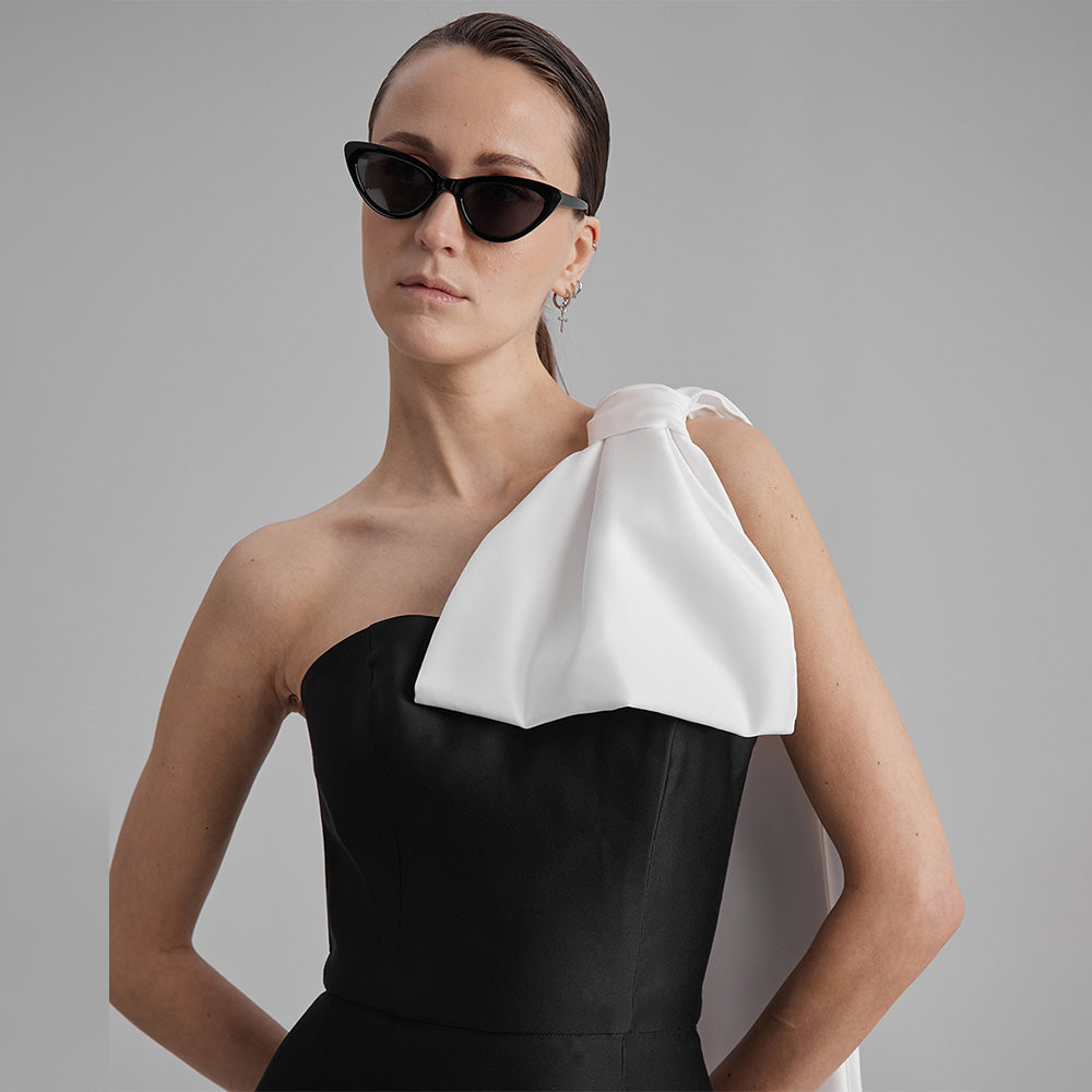 Explore our curation of timeless designer dresses with Gigi black strapless dress with a white cape bow that showcases an elegant silhouette. Shop now!