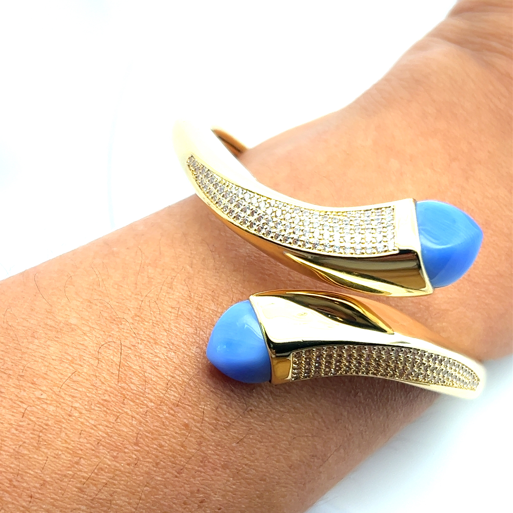 Elegant yellow gold plated wrap cuff bracelet with blue chalcedony crystals and pavé cubic zirconia accents. A luxe statement piece for every occasion. Shop premium jewelry online.