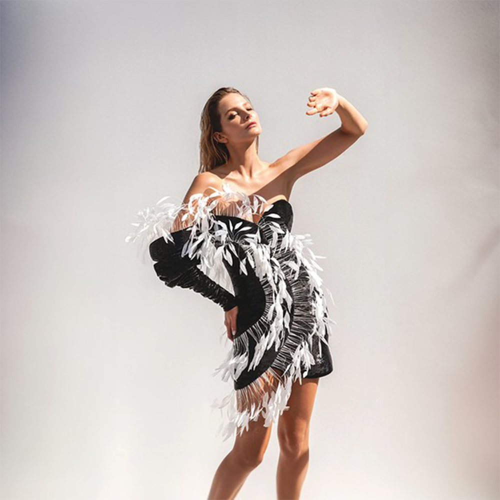 A mini dress in jet black sequins highlighted with a halo in white coq plumes.