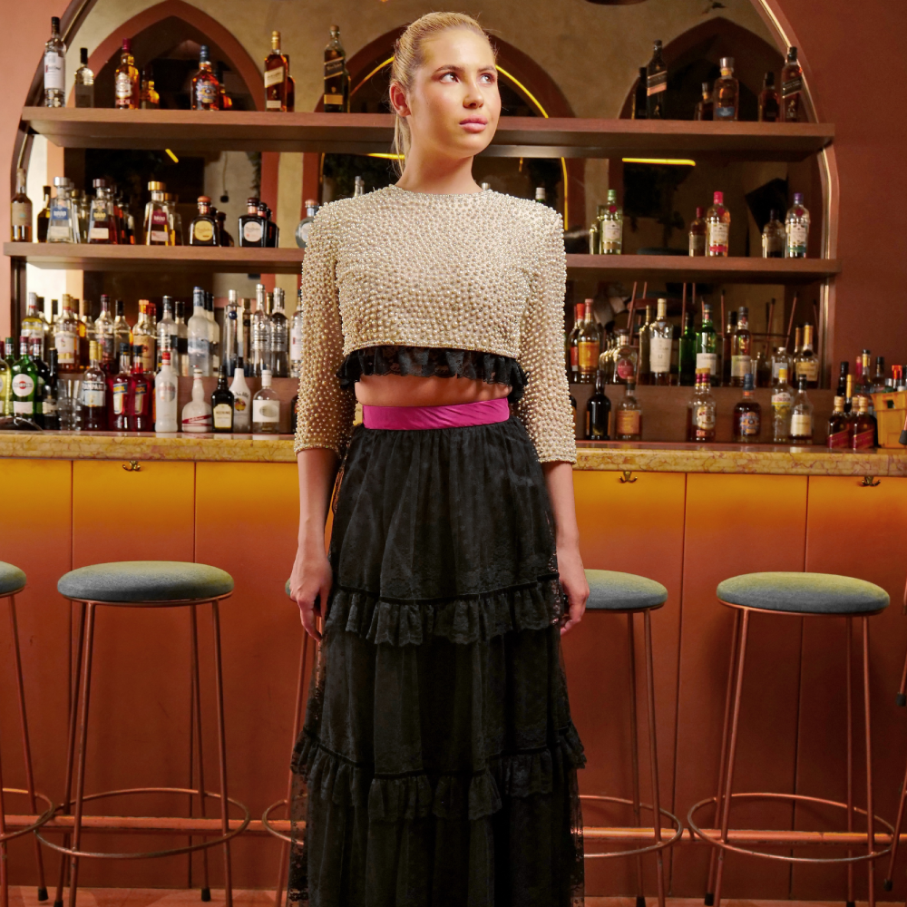 A long black tulle skirt with lace ruffles paired elegantly with a pearl-embroidered crop top and sleeves