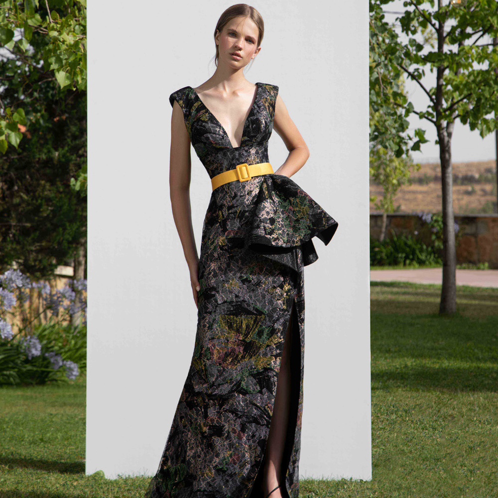 Deep V-neck on a straight printed lace gown with a side slit under a bell shape drapery.