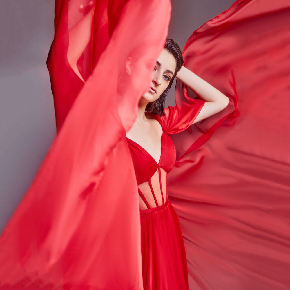 Long flared “Deep Red” Chiffon dress, with corset cut bodice and dramatic cape sleeves.