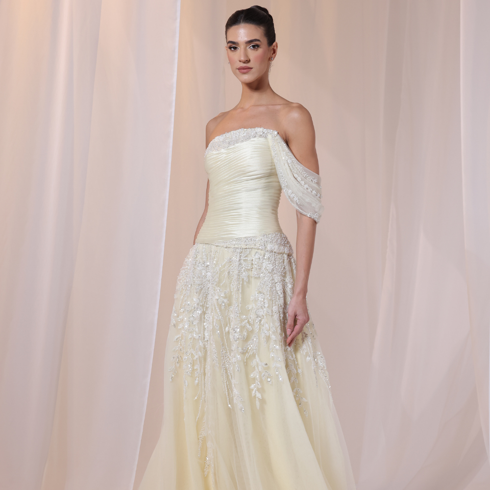 Shop online soft yellow gown with draped bodice, asymmetrical off-shoulder detail and embellished airy layers, perfect for special occasions.