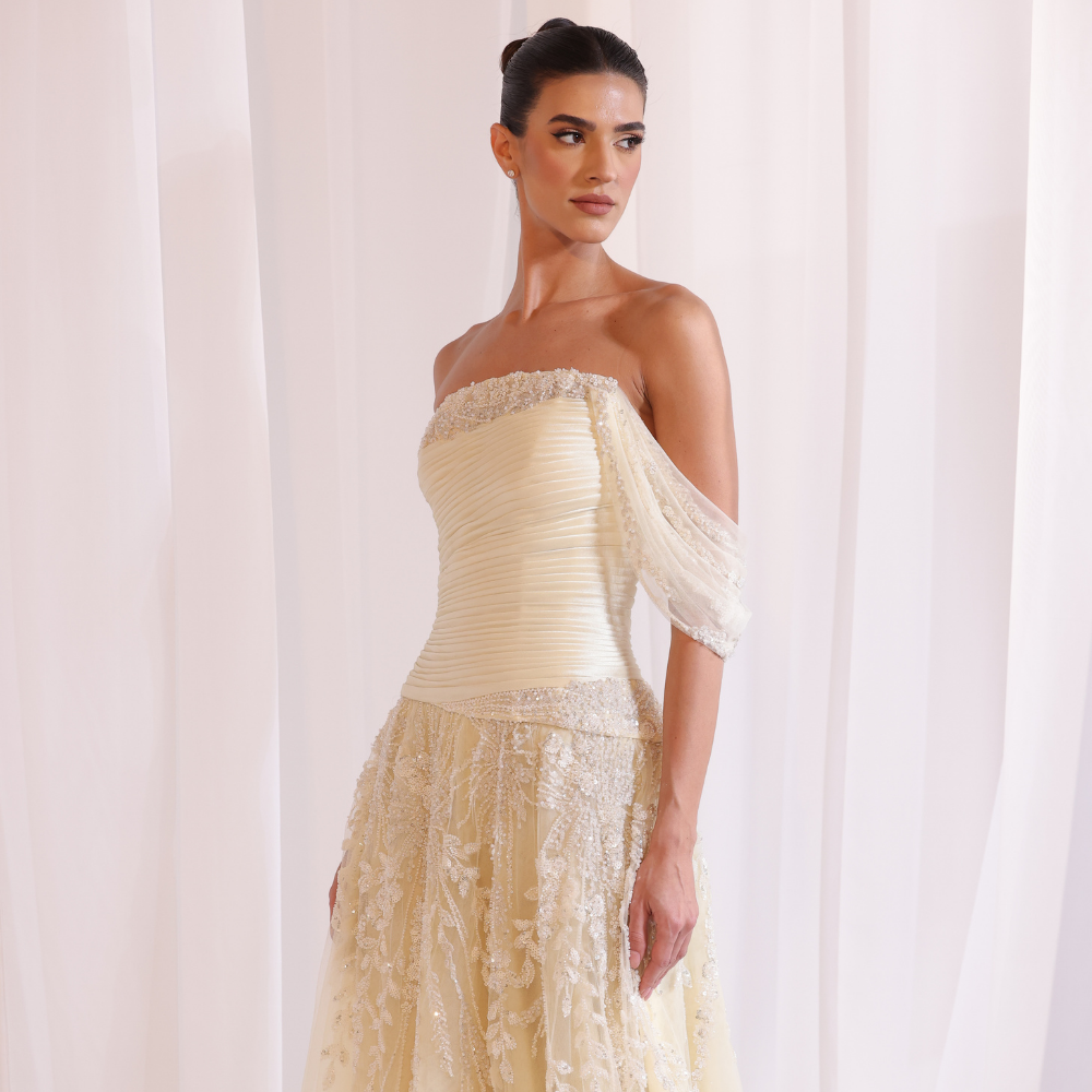 Shop online soft yellow gown with draped bodice, asymmetrical off-shoulder detail and embellished airy layers, perfect for special occasions.