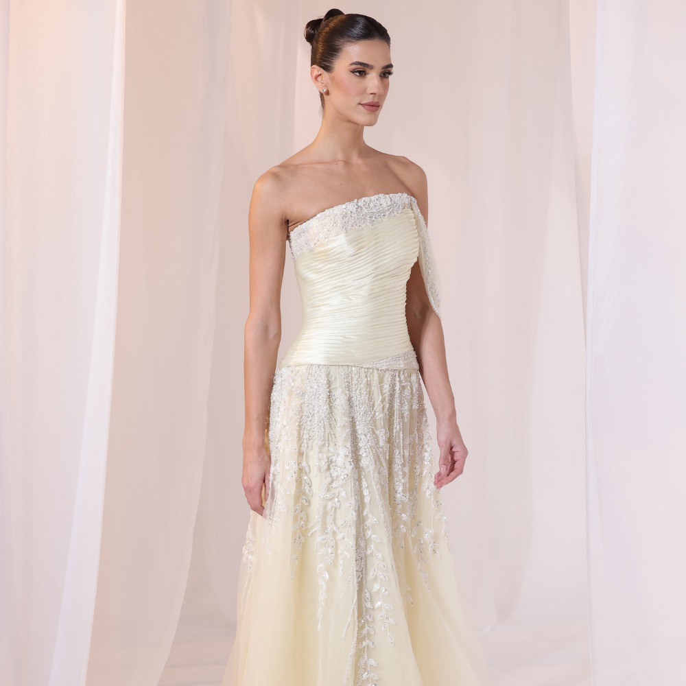 Shop online soft yellow gown with draped bodice, asymmetrical off-shoulder detail and embellished airy layers, perfect for special occasions.