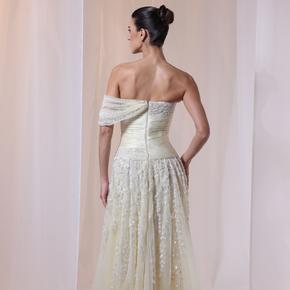 Shop online soft yellow gown with draped bodice, asymmetrical off-shoulder detail and embellished airy layers, perfect for special occasions.