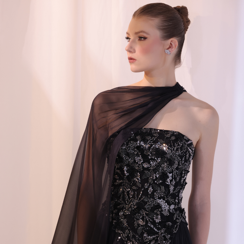 Shop online black gown with embellished strapless bodice, flowing silhouette and sheer one-shoulder drape, perfect for parties and special occasions.