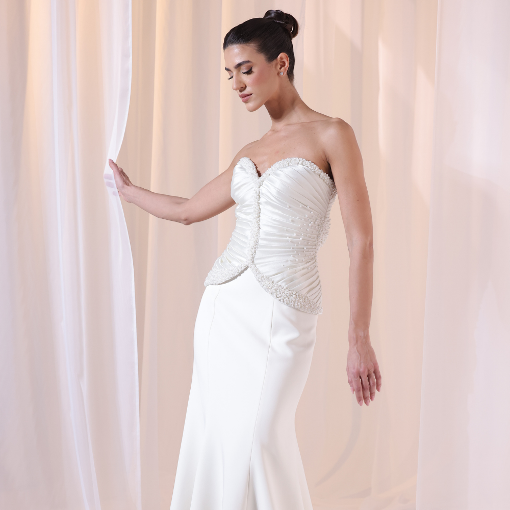 Shop online timeless ivory gown with structured corset, delicate ruching and flowing silhouette, perfect for weddings, receptions and special occasions.