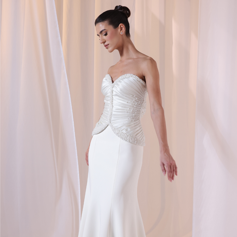 Shop online timeless ivory gown with structured corset, delicate ruching and flowing silhouette, perfect for weddings, receptions and special occasions.