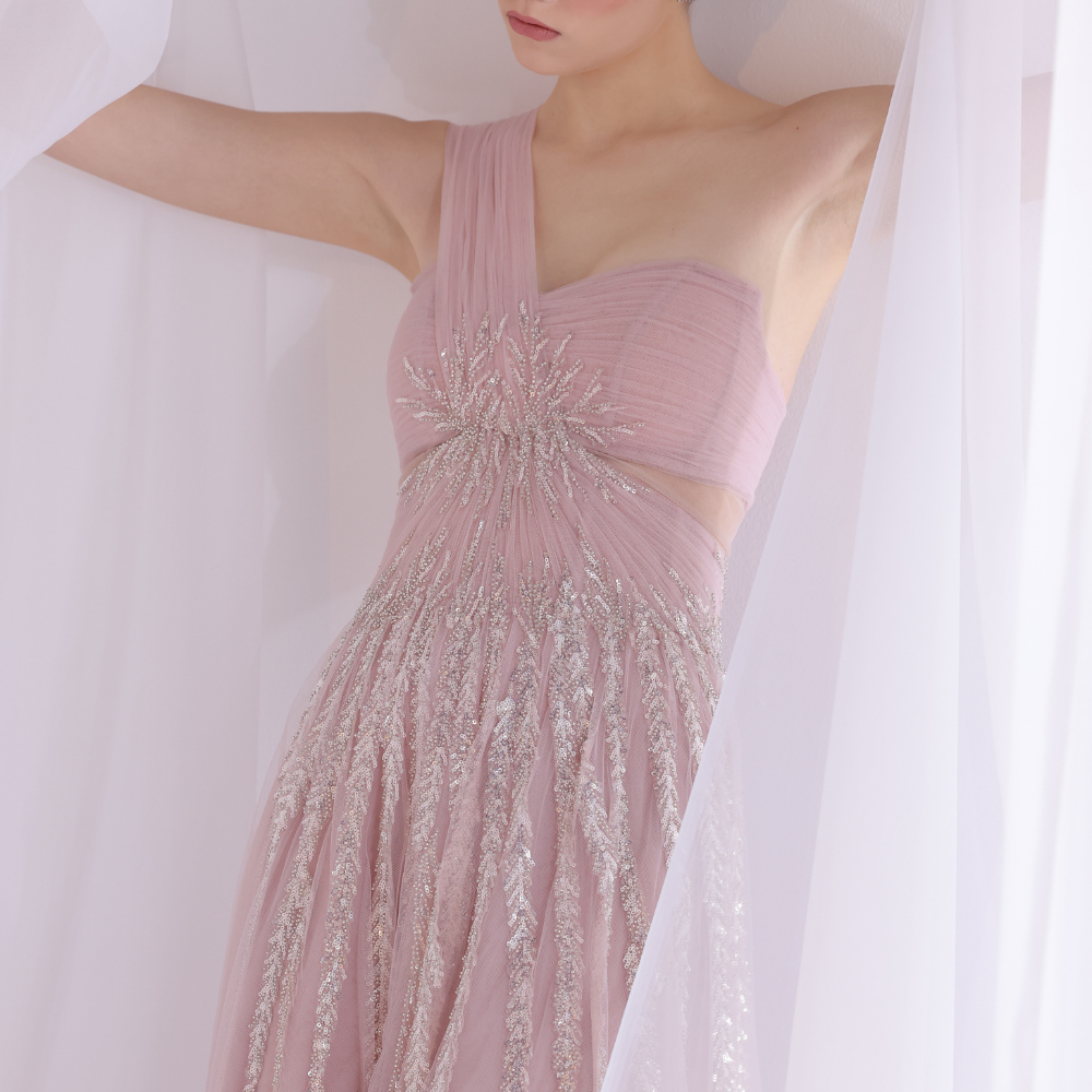 Shop online soft blush gown with one-shoulder silhouette, delicate shimmer detailing and flowing airy skirt, perfect for parties and special occasions.
