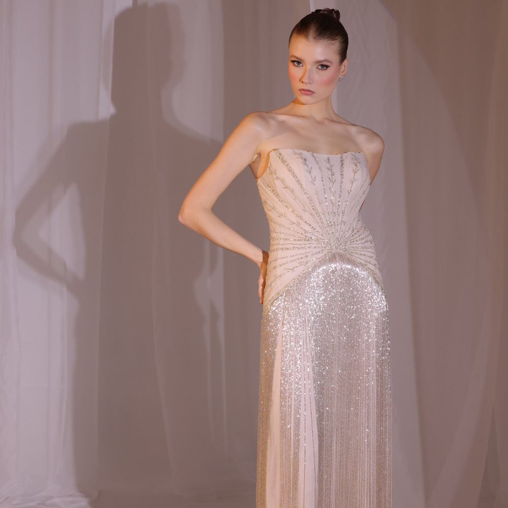 Shop online blush embellished gown with delicate detailing and fluid shimmering layers, inspired by Charleston elegance and perfect for special occasions.