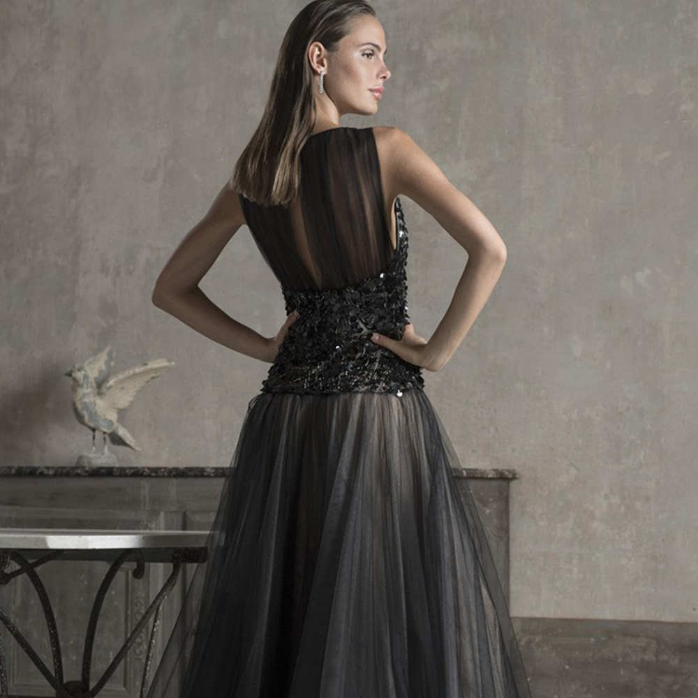 Sheath gown in illusion tulle and silk georgette with deep neckine and bodice hand beaded with sequins.