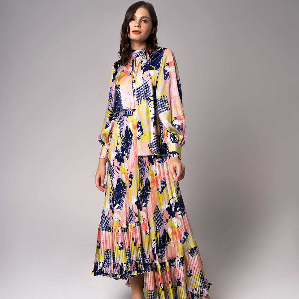 With hints of bold colors and patterns, this modest dress features a pleated flare, a feminine waist band with an elegant neckline.