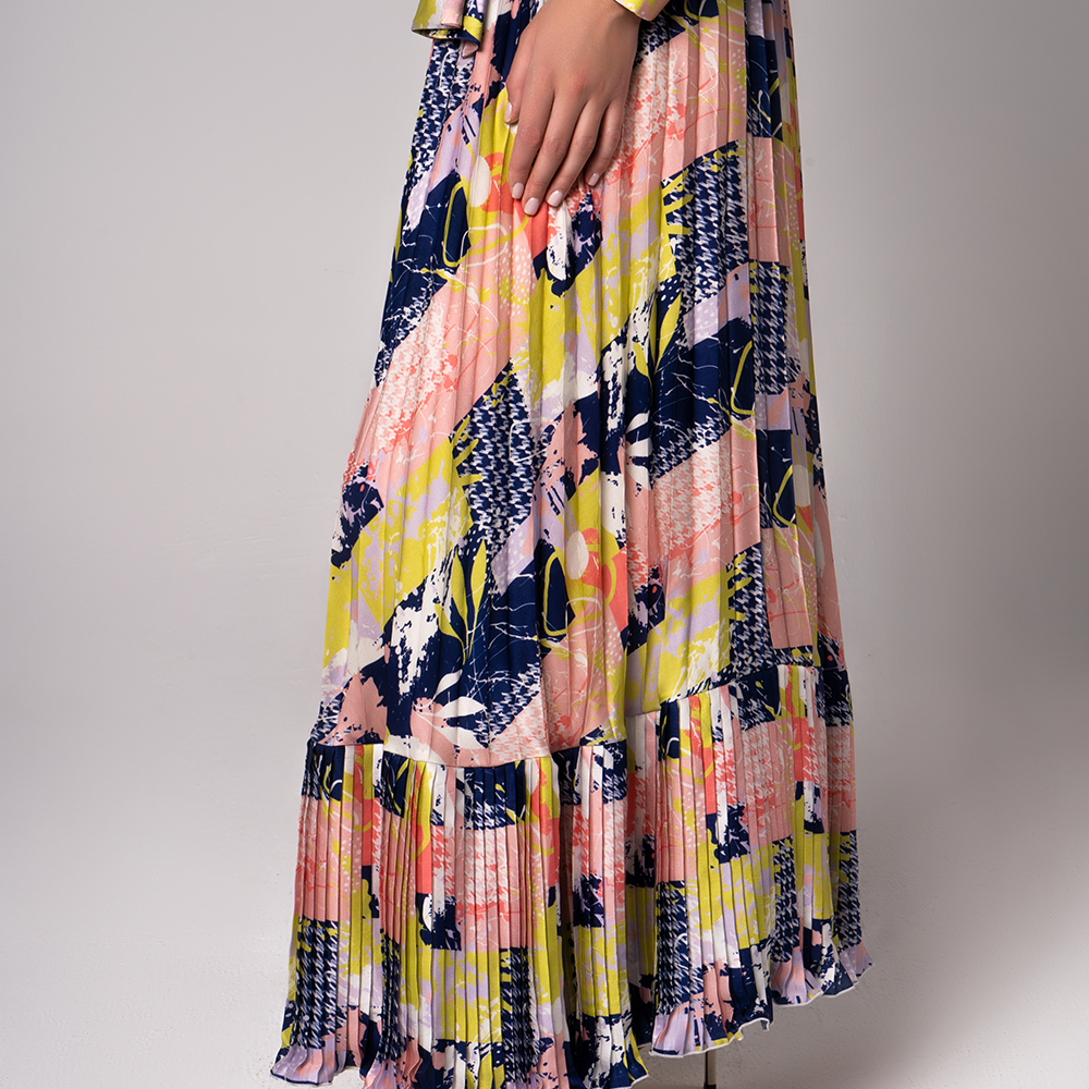 With hints of bold colors and patterns, this modest dress features a pleated flare, a feminine waist band with an elegant neckline.