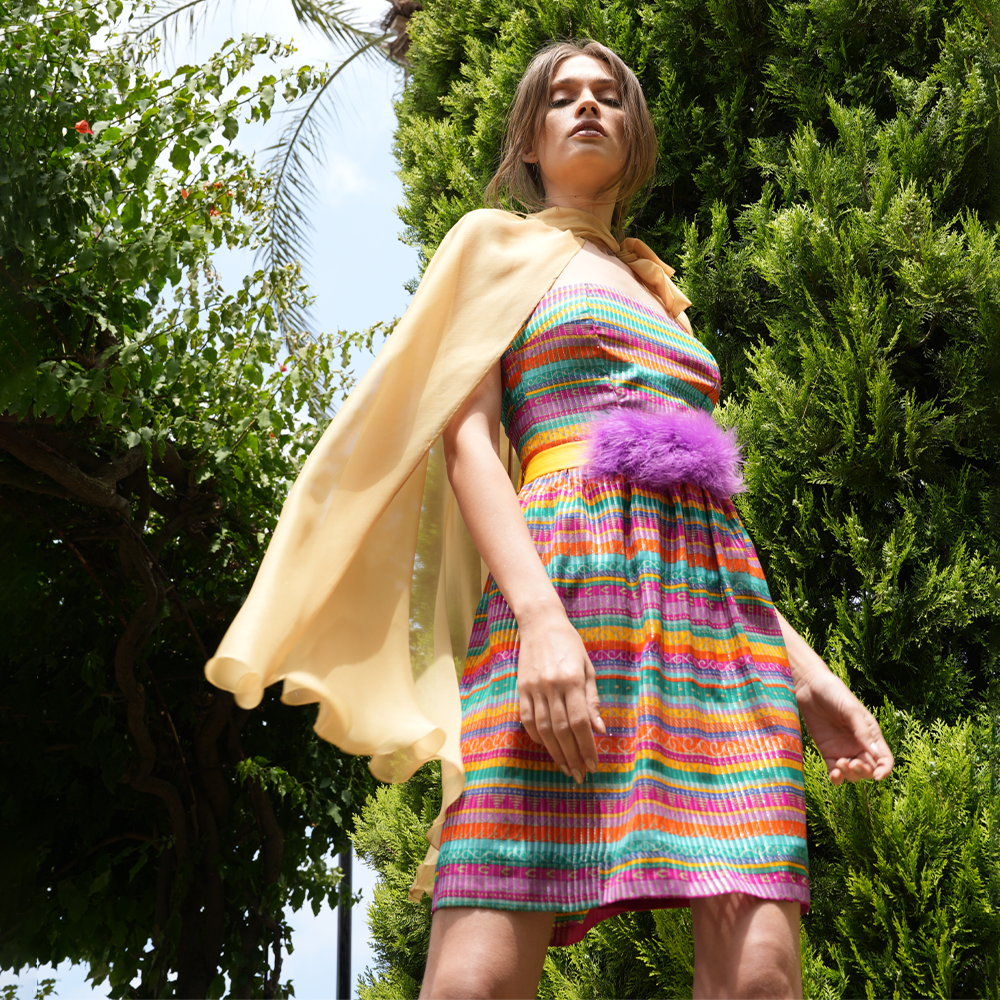 Multicolor short dress with gold chiffon cape and feather belt.