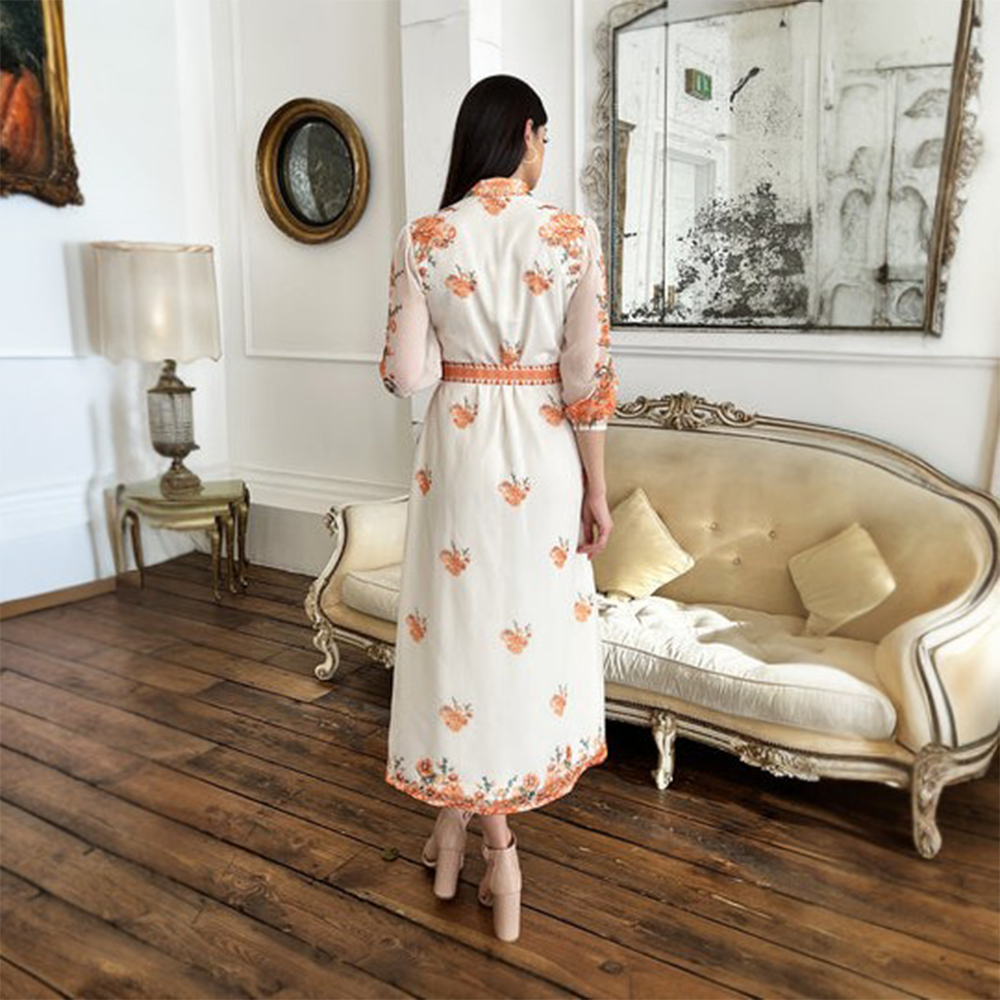 The Rose dress is a white midi-length dress featuring a stunning orange floral print with an adjustable belt