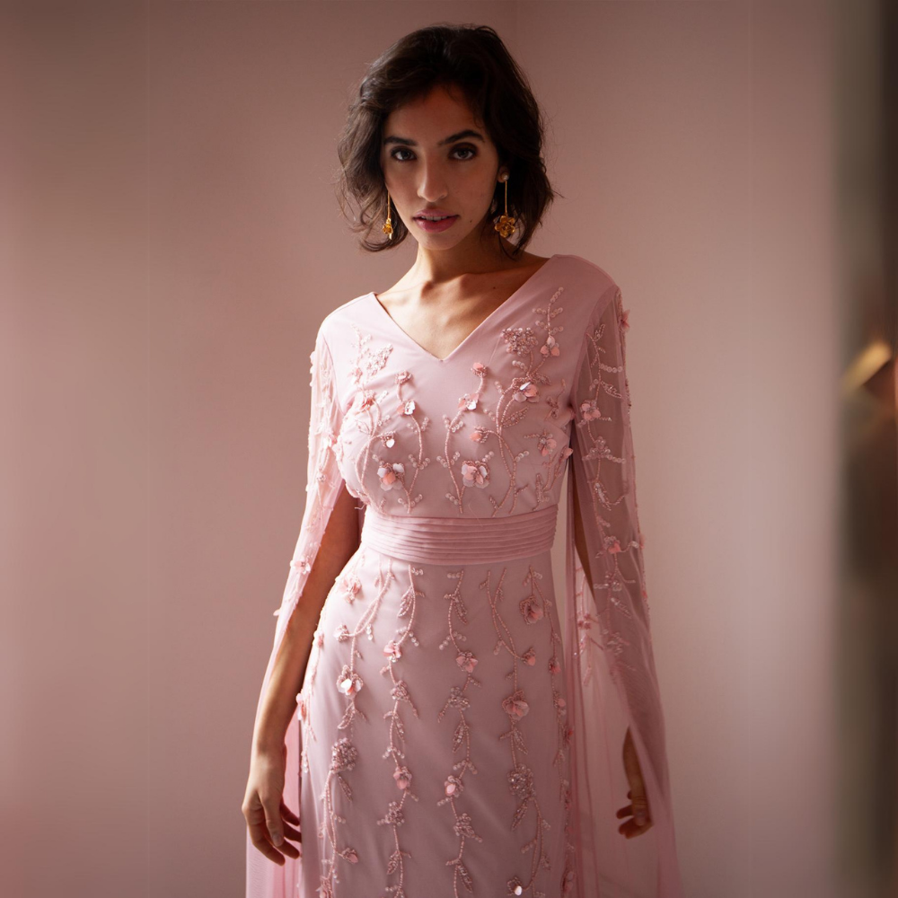 The Betsy Gown is a beautiful pale pink with mesh sleeves that cascade to the floor as well as pink floral sequins