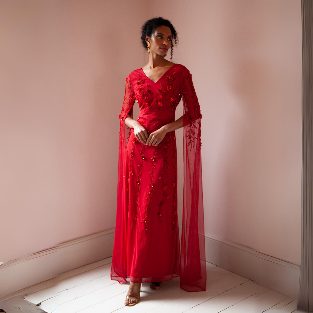The Betsy Gown is a rich red colour with mesh sleeves that cascade to the floor as well as red floral sequins