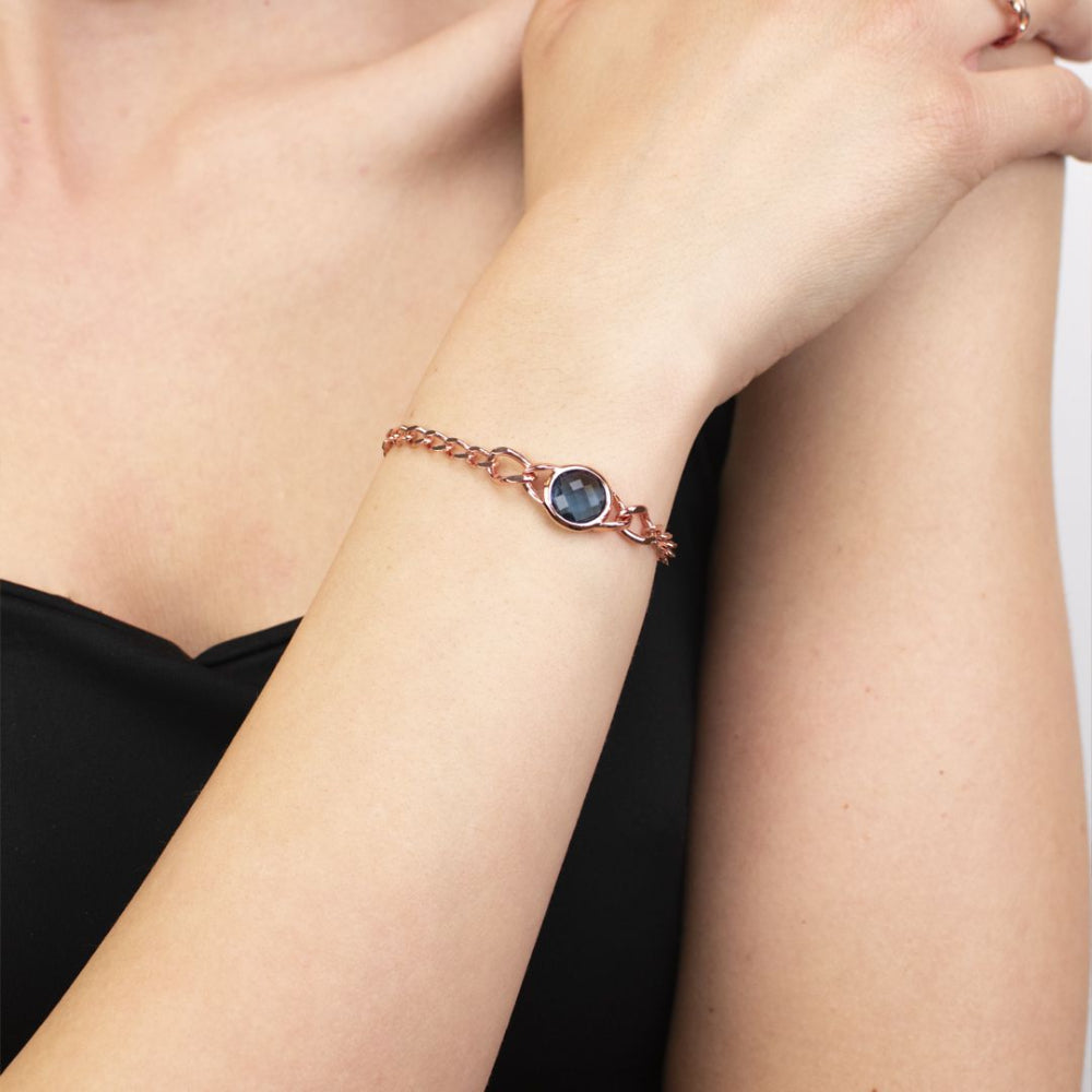 Rose gold plated bronze curb bracelet with a blue sapphire crystal interlayer pendant for a sleek modern statement. Shop premium jewelry online.