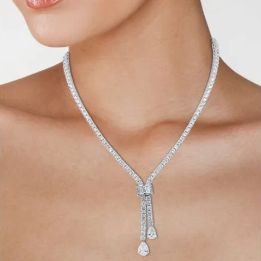 30CTTW Round Cubic Zirconia necklace with baguette and pear CZ double drop. Box clasp closure. Set in rhodium plated brass.
