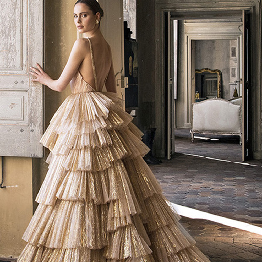 Bridal ball gown from iconic designer Peter Langner is a metallic pleated gold tulle asymmetric flounces and deep v neckline.