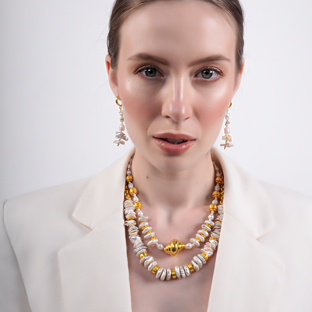 Inspired by the dance of sunlight on tranquil waters, this stunning necklace features lustrous pearls and golden beads