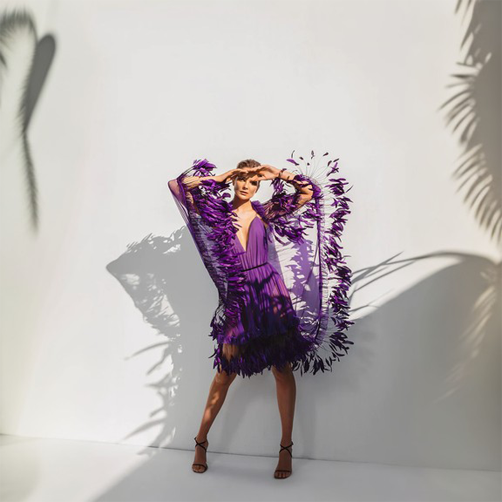 A purple silk chiffon mini-dress with an integrated scarf train and ruffled coq plumes.