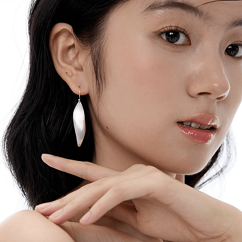 Discover the Silver Wind Leaf Drop Earrings at The Luxe Maison, featuring delicate leaf-inspired silhouettes crafted in sterling silver. Inspired by the graceful movement of leaves in the breeze, these elegant earrings bring a nature-inspired charm and effortless sophistication to everyday outfits and special occasions.