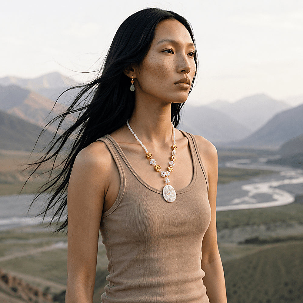 Discover the Tara Mother-of-Pearl Cameo Necklace at The Luxe Maison, featuring a hand-carved image of Tara seated upon a lotus, crafted from luminous natural mother-of-pearl. With its iridescent finish, delicate floral beads, and intricate detailing, this meaningful necklace blends traditional artistry with timeless elegance.