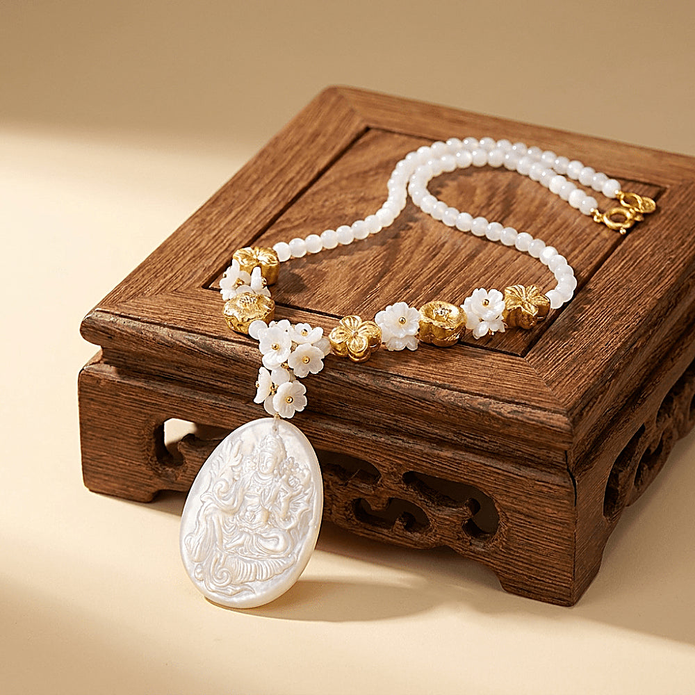 Discover the Tara Mother-of-Pearl Cameo Necklace at The Luxe Maison, featuring a hand-carved image of Tara seated upon a lotus, crafted from luminous natural mother-of-pearl. With its iridescent finish, delicate floral beads, and intricate detailing, this meaningful necklace blends traditional artistry with timeless elegance.