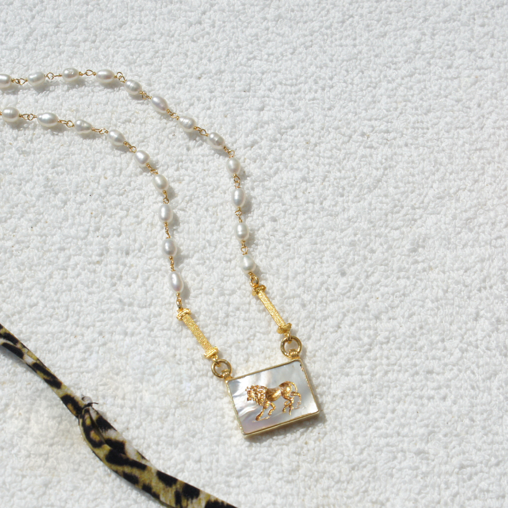 Shop the Aslan III Necklace adorned with sea pearls, and a lion engraving. Get this classic design from our jewellery collection for women. Shop now!