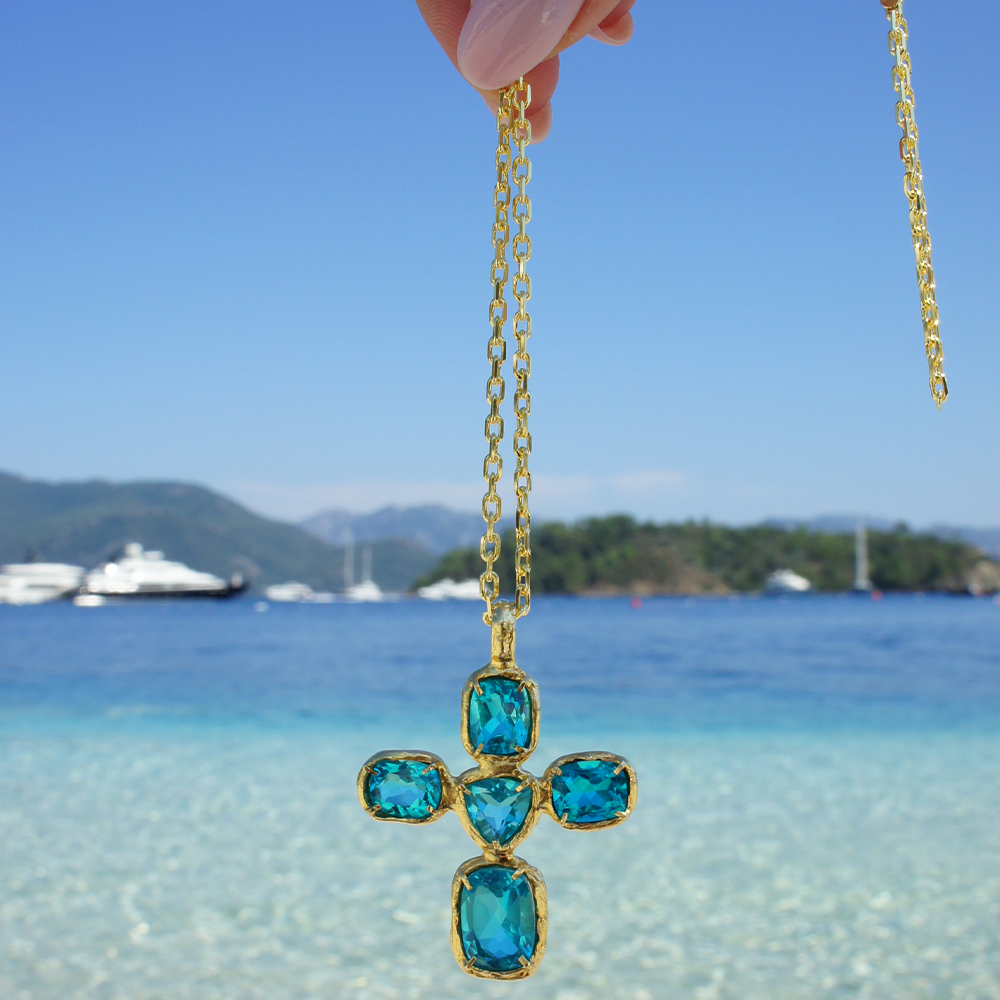 Aurora Cross: The combination of 22K Gold Vermeil & 5 hand-selected Blue Topaz gemstones. Shop this classic design online at The Luxe Maison. Shop now!